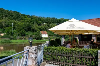 a restaurant with an umbrella next to a river at Hotel U Berounky in Srbsko
