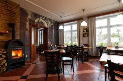 a restaurant with a fireplace and tables and chairs at Hotel U Berounky in Srbsko