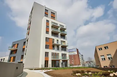a tall white building in front of two buildings at Residence Nad Vltavou in Prague