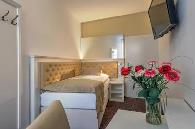 a bedroom with a bed and a vase of red flowers at Hotel Taurus in Prague