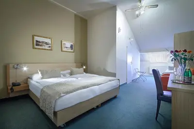 a bedroom with a bed and a table and a chair at Hotel Taurus in Prague