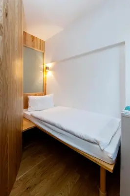 a bed in a small room with a mirror at Hotel Wolf in Prague