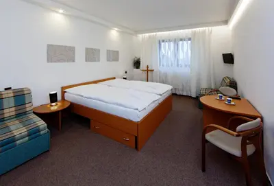 a bedroom with a large bed and a chair at Hotel Wolf in Prague
