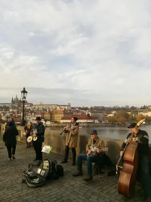 a group of people playing instruments next to a river at apartricanova in Prague
