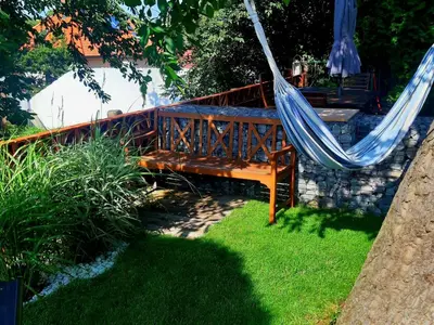 a wooden bench with a hammock in a yard at Holiday Home Řeporyje by Interhome in Prague