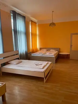 two beds in a large room with yellow walls at Hotel Praha Club bed & breakfast in Prague