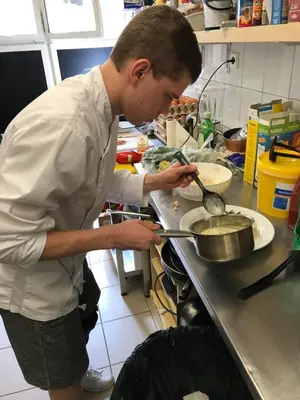 a man is preparing food in a kitchen at Hotel Praha Club bed & breakfast in Prague