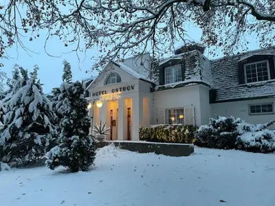 a house with a christmas lighted front door in the snow at Hotel Ostrov in Nymburk