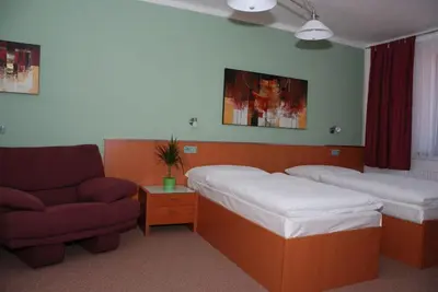 a room with two beds and a couch and a chair at Hotel Ostrov Garni in Sadská