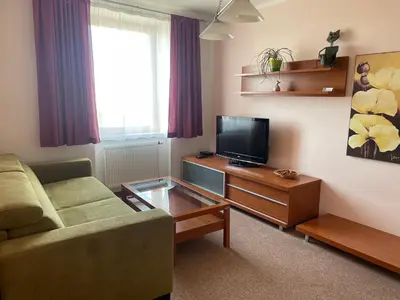a living room with a couch and a flat screen tv at Hotel Ostrov Garni in Sadská