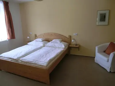 a bedroom with a large bed and a chair at Pension Rondel in Poděbrady