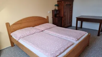 a wooden bed with pink pillows on it in a room at Pension Rondel in Poděbrady