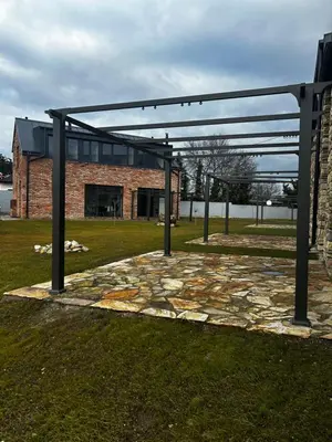 a stone patio with a metal structure in front of a building at Palace Resort Jíloviště in Jíloviště