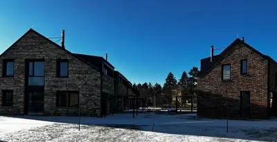 two large brick buildings with snow on the ground at Palace Resort Jíloviště in Jíloviště