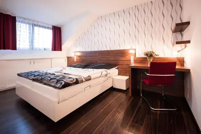 a bedroom with a bed and a desk with a red chair at Hotel Pivovar in Prague
