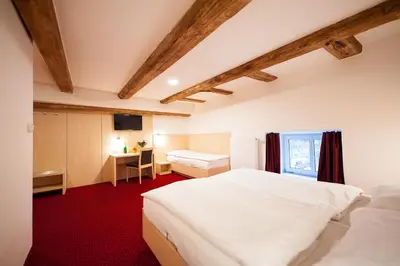a bedroom with a large white bed and a desk at Hotel Pivovar in Prague