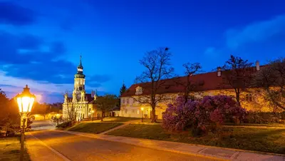 a street with a building and a clock tower at night at Loreta Hotel in Prague