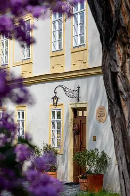 a white building with yellow windows and a door at Loreta Hotel in Prague