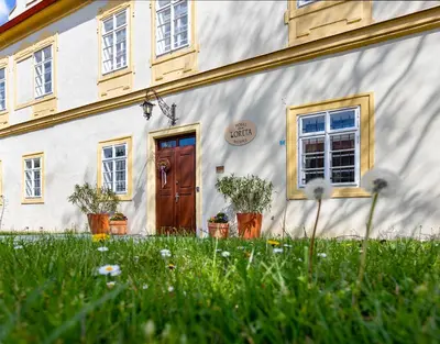 a white building with a wooden door and some plants at Loreta Hotel in Prague