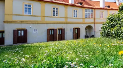a building with brown doors and a field of flowers at Loreta Hotel in Prague