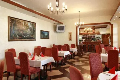 a restaurant with tables and chairs and a chandelier at Golf Resort Hotel Konopiště in Benešov