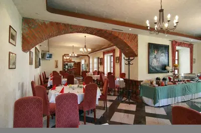 a dining room with tables and chairs in a restaurant at Golf Resort Hotel Konopiště in Benešov