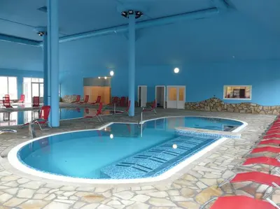 a large swimming pool in a building with blue walls at Golf Resort Hotel Konopiště in Benešov