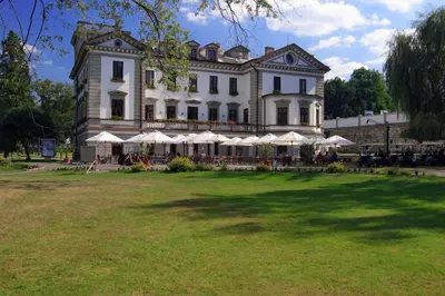 a large building with tables and umbrellas in front of it at Golf Resort Hotel Konopiště in Benešov
