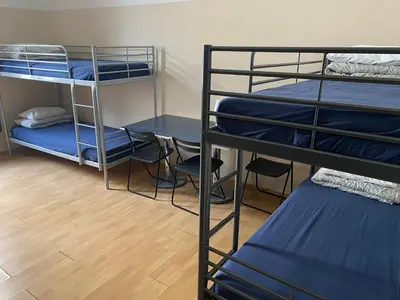 a room with three bunk beds and a table and chairs at Hostel EMMA in Prague