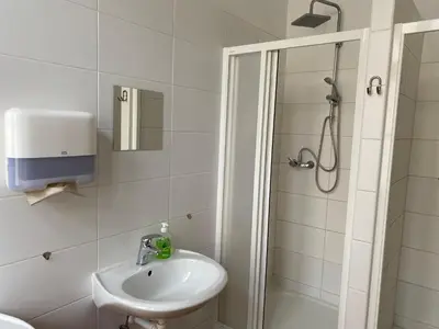 a white bathroom with a sink and a shower at Hostel EMMA in Prague
