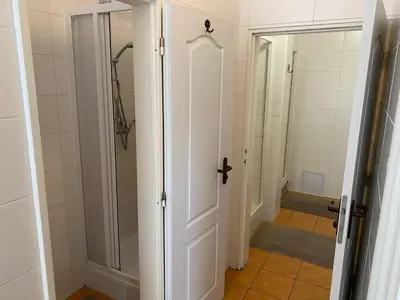 a bathroom with a shower and a white door at Hostel EMMA in Prague