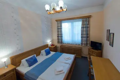 a bedroom with a bed and a table and a window at Hotel Soudek in Poděbrady