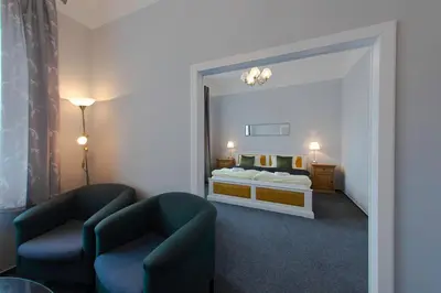 a room with a bed and two chairs and a mirror at Hotel Soudek in Poděbrady