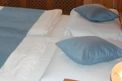 a white bed with blue pillows on it at Hotel Soudek in Poděbrady