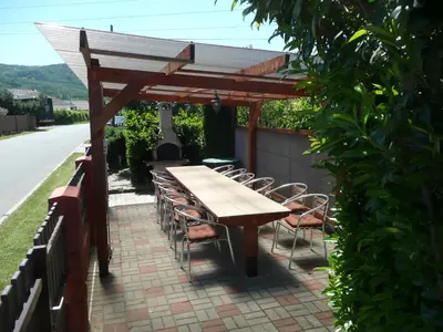 a wooden table and chairs under a wooden pergola at Penzion U Tulaka in Dobřichovice