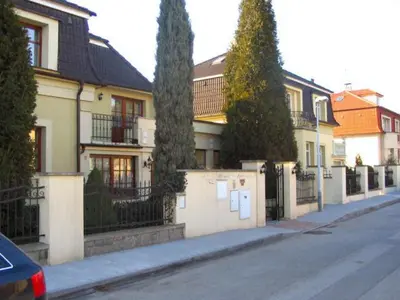 a house with a fence and trees on a street at Villa Olivia in Prague