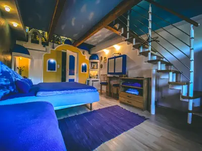 a bedroom with a blue bed and a staircase at Resort Svět in Úžice