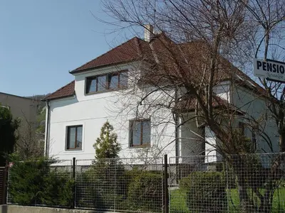 a white house with a fence in front of it at Pension Nostalgie in Beroun
