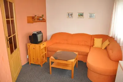 a living room with an orange couch and a tv at Pension Nostalgie in Beroun