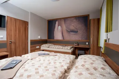 a bedroom with two beds and a large painting on the wall at Hotel U koně in Beroun