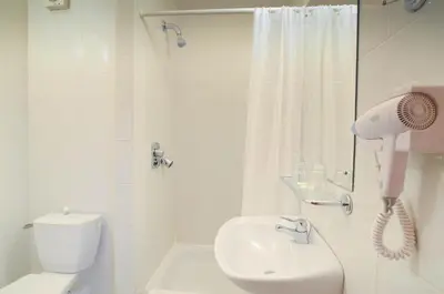 a white bathroom with a shower and a blow dryer at Hotel ILF in Prague