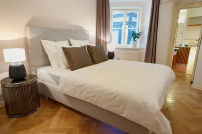 a bedroom with a large white bed and a lamp at U Kapra Apartments in Prague