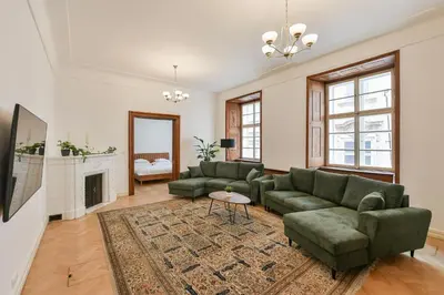 a living room with two green couches and a fireplace at U Kapra Apartments in Prague
