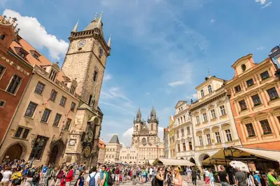 a crowd of people walking around a city with a clock tower at U Kapra Apartments in Prague