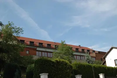 a brick building with a red roof and trees at Hotel Chvalská Tvrz in Prague
