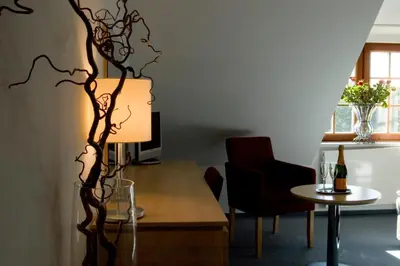 a living room with a table and a lamp at Hotel Chvalská Tvrz in Prague