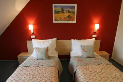 two beds in a hotel room with red walls at Hotel Chvalská Tvrz in Prague