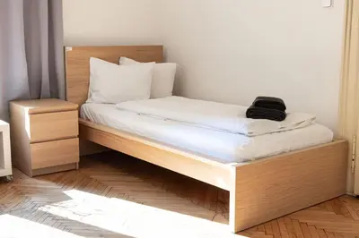 a bed with white sheets and a black bag on it at Apartments in Mala Strana - 10 minutes from Charles Bridge in Prague