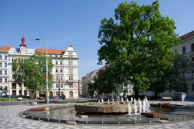 a fountain in a square with a tree and buildings at Apartments in Mala Strana - 10 minutes from Charles Bridge in Prague