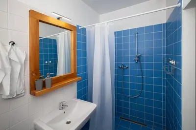 a blue tiled bathroom with a sink and a shower at Žižkov Cosy Studio Apartments in Prague